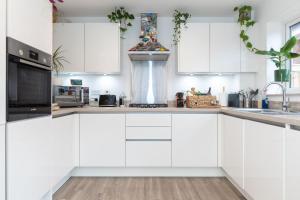 a white kitchen with white cabinets and a sink at Detached house with Netflix, gym, garden, BBQ, coffee and more in Tile Hill