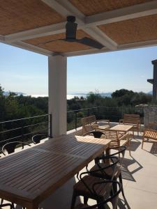 un patio con una mesa de madera y sillas en el techo en Villa Mytikas, luxury in Greece with seaview and heated pool & jacuzzi, en Pogoniá