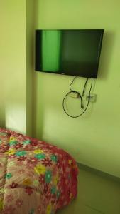 einen Flachbild-TV, der an einer Wand neben einem Bett hängt in der Unterkunft OSAKA RIVERVIEW in Tangerang