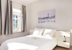 una camera da letto bianca con un letto bianco e una finestra di Ille a Wittdün