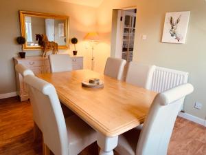a dining room with a wooden table and white chairs at The Lodge in Kelso