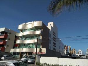 un gran edificio con coches estacionados frente a él en Flat beira mar Manaíra, en João Pessoa