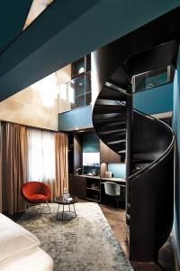 a hotel room with a spiral staircase and a red chair at Aiola Living Graz in Graz