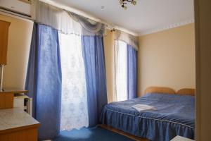 Schlafzimmer mit blauem Bett und blauen Vorhängen in der Unterkunft Вілла Калина in Truskawez