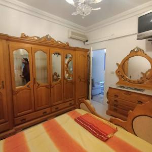 a bedroom with a wooden cabinet and a mirror at S+2 skanes RDC enozha in Monastir