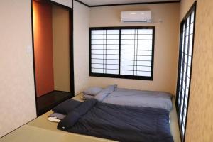 Bett in einem Zimmer mit einem großen Fenster in der Unterkunft Linore in Ginowan