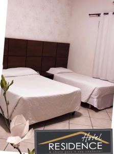 2 camas en una habitación con un cartel que lee la residencia del hotel en Hotel Residence, en Dourados