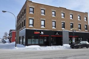 a building on a street with a car parked in front at Le Chic-Urbain in Rouyn