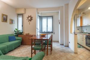 eine Küche und ein Wohnzimmer mit einem Tisch und einem grünen Sofa in der Unterkunft Appartamento Elisa 100 metri dal mare in Finale Ligure