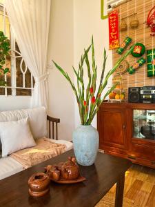 una sala de estar con una mesa con un jarrón. en Phòng Mơ - Nhà Mơ Homestay Bến Tre, en Ben Tre