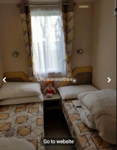 a bedroom with two beds and a window at Susie's Beautiful Caravan near the sea in Pwllheli