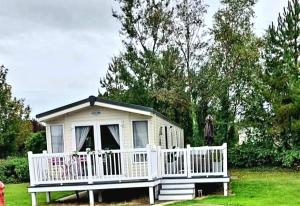a small white house with a white fence at Susie's Beautiful Caravan near the sea in Pwllheli