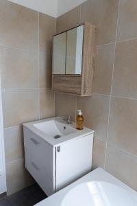 y baño con lavabo blanco y espejo. en Maison au pied du château, en Châteaudun