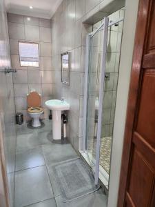 a bathroom with a toilet and a sink and a shower at Suits Guest house & bar in Carletonville