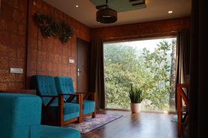 a waiting room with blue chairs and a large window at Vayalada Valley View Resort in Bālūssheri