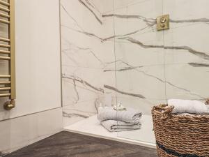 a bathroom with a shower with towels and a basket at Whisk Away Cottage in Penrith +48 photos