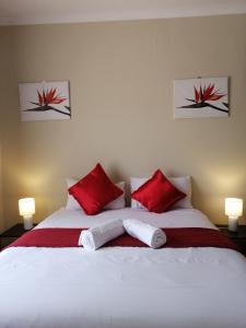 a bedroom with a white bed with red pillows at Beautiful & Serene Airbnb house in Klerksdorp