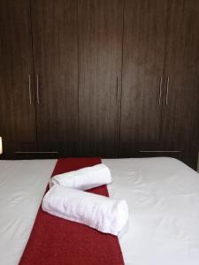 1 dormitorio con 2 toallas en una cama con armarios de madera en Beautiful & Serene Airbnb house en Klerksdorp