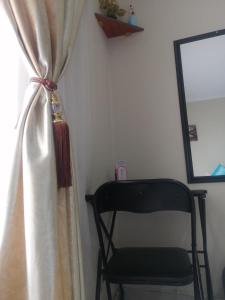 una silla negra junto a una ventana con cortina en Beautiful & Serene Airbnb house en Klerksdorp
