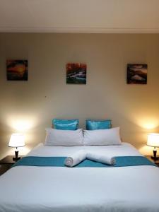 a bedroom with a large white bed with two lamps at Beautiful & Serene Airbnb house in Klerksdorp +21 photos