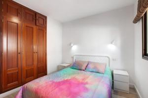 a bedroom with a bed with a colorful blanket at Apto Aguacada in Punta del Hidalgo