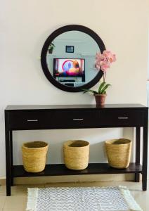 un espejo sobre una consola negra con cestas en Winnie's Cozy Home, en Iringa
