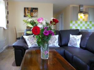 a vase of flowers sitting on a coffee table at ROSE - 2 Bedroom Cottage in Kingsnorth