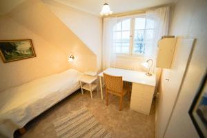 a small bedroom with a bed and a desk and a window at Liljeholmen Herrgård Hostel in Rimforsa