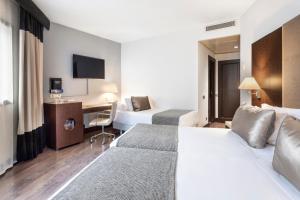 a hotel room with two beds and a desk at Catalonia El Retiro in Madrid