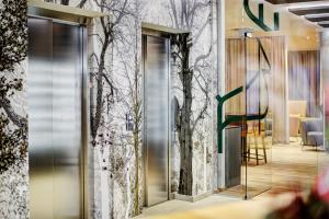 a lobby with mirrored doors and trees on the wall at Königswieser Hof in Königswiesen