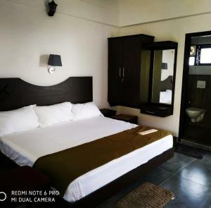 a bedroom with a large white bed and a mirror at Zadokz farmstay in Padinjarathara