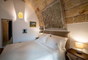 a bedroom with a white bed and a stone wall at Quintessenza Luxury Domus in Polignano a Mare