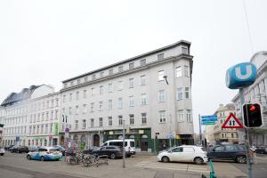 een groot gebouw aan een drukke stadsstraat met auto's bij Self-Check-In & Perfect Metro Connection I in Wenen