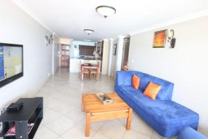 a living room with a blue couch and a table at Cozumel 113 in Umdloti