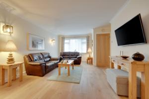 a living room with leather furniture and a flat screen tv at Clover Cottage in Begelly