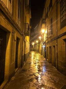 una calle de ciudad vacía por la noche con luces en Agarimo das Burgas en Ourense