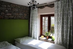 a bedroom with a green wall and two beds and a window at Tunnel Cottages at Blaen-nant-y-Groes Farm in Aberdare