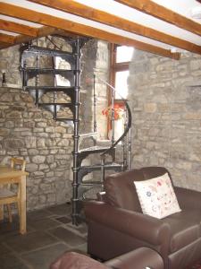 a living room with a spiral staircase in a stone wall at Tunnel Cottages at Blaen-nant-y-Groes Farm in Aberdare