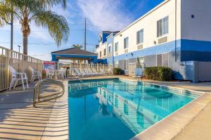 a swimming pool with chairs next to a building at Days Inn by Wyndham Lathrop in Lathrop