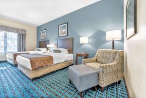 a hotel room with two beds and a chair at Wingate by Wyndham Schaumburg in Schaumburg