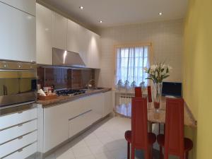 a kitchen with white cabinets and a table with red chairs at San Marco2 Apartment in Venice