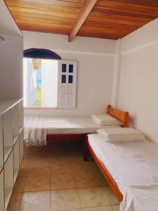 two beds in a room with a window at Alma Tropical Resort in Vera Cruz de Itaparica