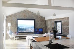 a kitchen and living room with a couch and a tv at Quinta Milhão - Casa do Pomar in Guimarães