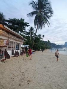 a group of people walking on a beach with a palm tree at ALFA Beach Front Lodge in El Nido