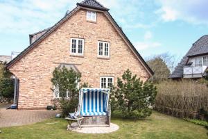 a blue and white striped chair in front of a house at Hermes Hü in Wenningstedt