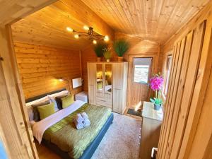 ein Schlafzimmer mit einem Bett in einer Holzhütte in der Unterkunft Yealm Cabin Self Catering Log Cabin in Devon with Hot Tub in Plymouth