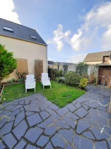 two white benches sitting on a patio in a yard at Maison de caractère bretonne « L’entre deux » in Le Vivier-sur-Mer