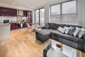 een woonkamer met een bank en een keuken bij Modern & spacious 2-bed flat with secure parking in Reading