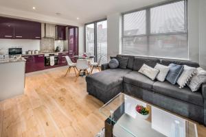 a living room with a couch and a kitchen at Modern & spacious 2-bed flat with secure parking in Reading