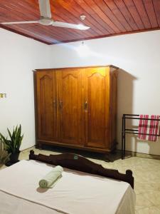 - une chambre avec un lit et une armoire en bois dans l'établissement Sun and Sand Apartment, à Ahangama